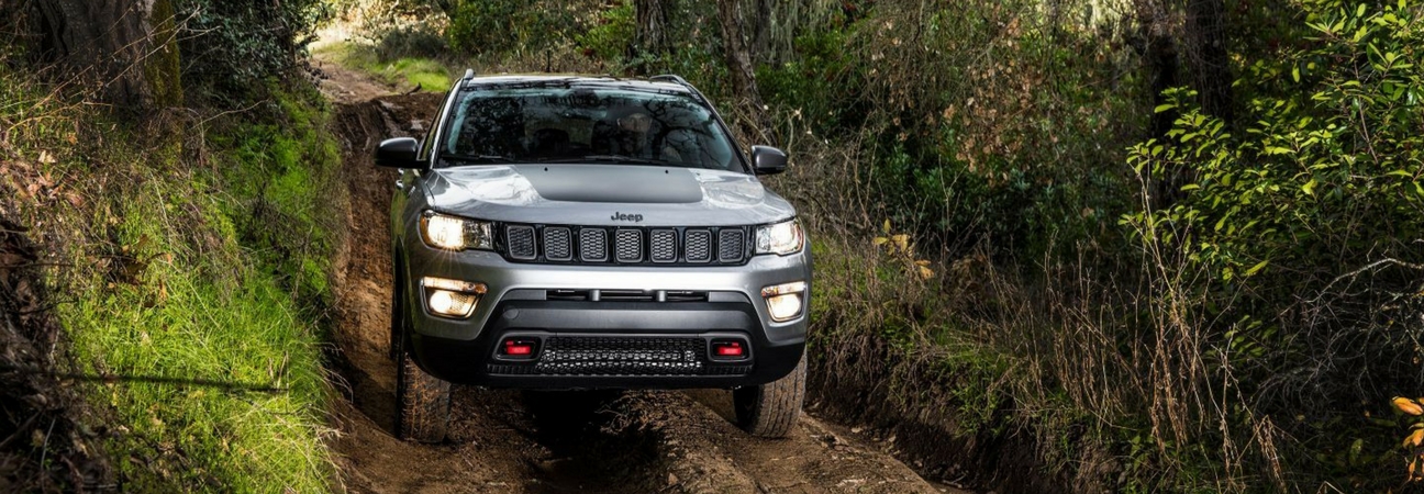 2018 Jeep Compass driving down a muddy path