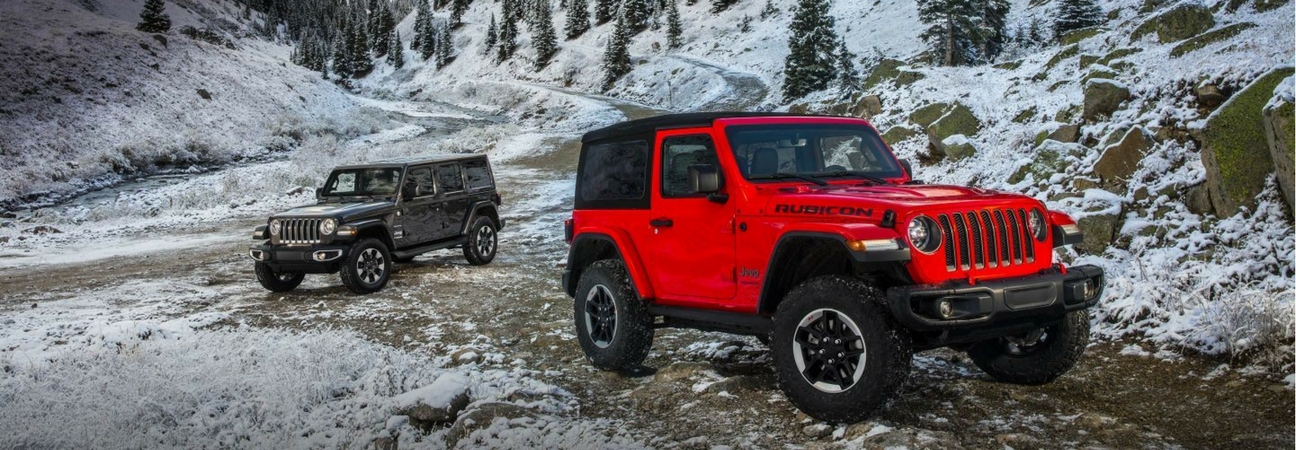 Two 2018 Jeep Wrangler SUVs parked on a snowy mountain