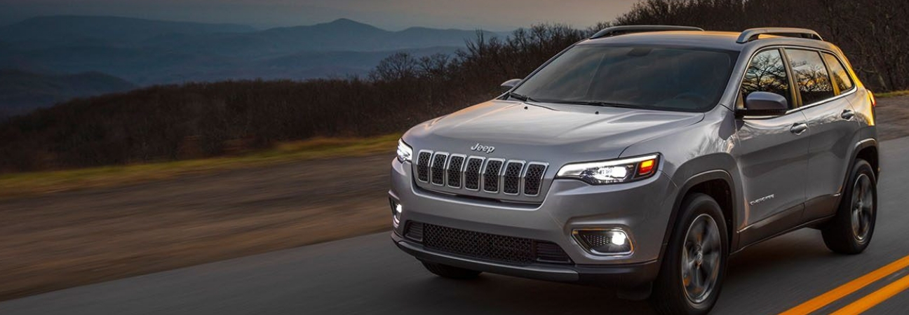 Silver 2019 Jeep Cherokee driving down mountain highway