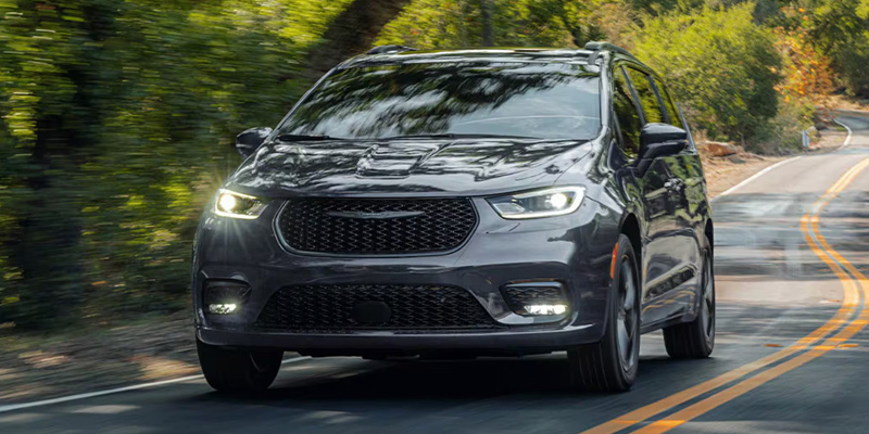 A 2026 Chrysler Pacifica driving on a road, showcasing its family-friendly design and spacious interior.